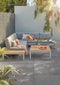 Outdoor Porcelain Tile Bluestone Light Grey being used outside with a grey, outdoor sofa set and matching table.