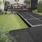 Lifestyle image of the House of Mosaics outdoor porcelain Black Slate tile, showing the tiles being used as stepping stones leading to a raised area for a perfect outdoor living space